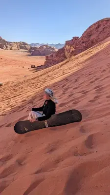 a woman sitting on the sand in the desert at Ahmad desert camp wadi rum in Wadi Rum