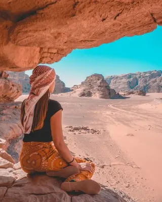 a woman sitting on a rock in the desert at Ahmad desert camp wadi rum in Wadi Rum