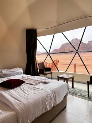 a bedroom with a bed and a large window at Golden Stars Luxury Camp Wadi Rum in Wadi Rum