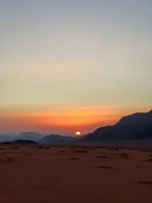 a sunset in the desert with mountains in the background at Local experience in El Quweira