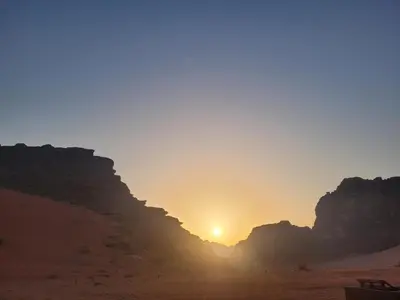 a sunset in the desert with mountains in the background at Wadi rum Breeze of calm in Wadi Rum