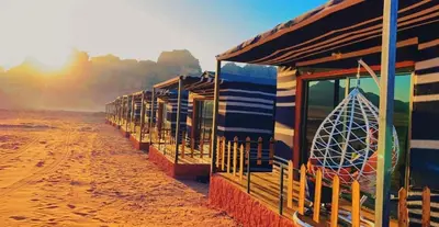 a row of houses on the beach with a surfboard at Nile Bedouin Camp in Disah
