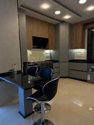 a kitchen with a black counter and two chairs at Luxury apartment شقة فخمة in Amman