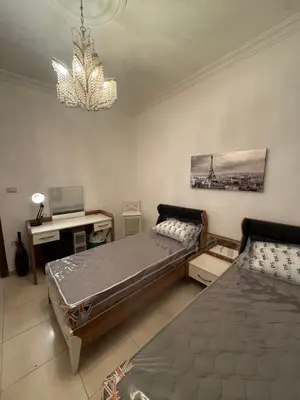 a bedroom with two beds and a desk and a chandelier at Furnished luxurious apartment with a stunning view near Kling Hussein Business Park in Amman