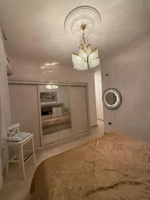 a bedroom with a bed and a mirror and a chandelier at Furnished luxurious apartment with a stunning view near Kling Hussein Business Park in Amman
