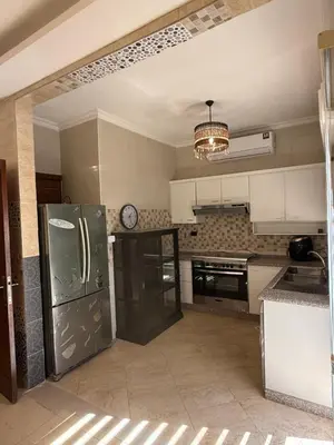 a kitchen with white cabinets and a black refrigerator at Furnished luxurious apartment with a stunning view near Kling Hussein Business Park in Amman