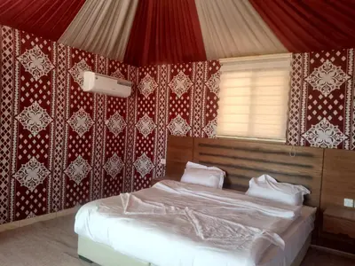 a bedroom with a bed with red and white wallpaper at Wadi Rum Adventure Camp & Tour in Wadi Rum
