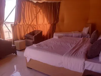 a hotel room with two beds and a chair at Wadi Rum Adventure Camp & Tour in Wadi Rum
