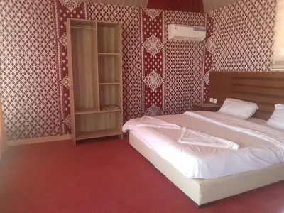 a bedroom with a large bed and red wallpaper at Wadi Rum Adventure Camp & Tour in Wadi Rum