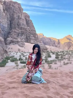 a woman sitting on the sand in the desert at Siella Pearl of Wadi Rum in Wadi Rum