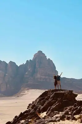 two people standing on a rock in the desert at Luxury Wadi Rum Camp in Wadi Rum
