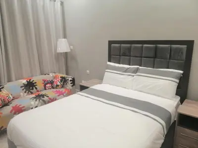a bedroom with a large bed and a chair at Pasha Holiday - DAMAC Tower in Amman