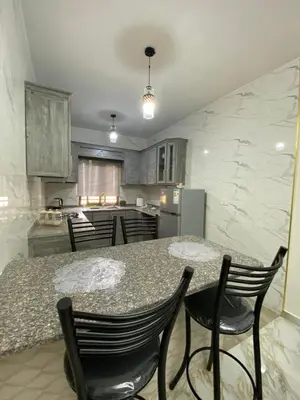a kitchen with a table and chairs and a kitchen with a counter at Travelers Choice Apartment Near Petra in Wadi Musa