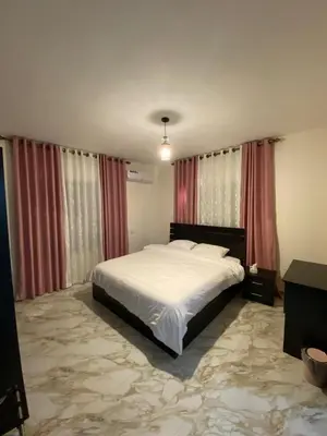 a bedroom with a white bed and red curtains at Travelers Choice Apartment Near Petra in Wadi Musa