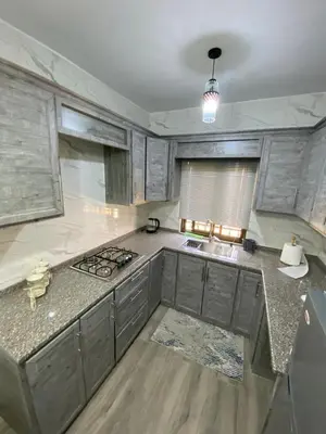 a kitchen with gray cabinets and a counter top at Travelers Choice Apartment Near Petra in Wadi Musa