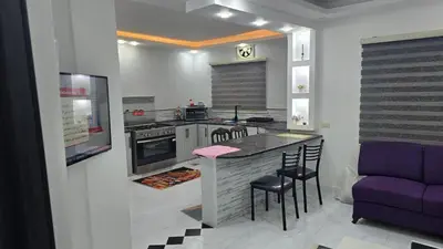 a kitchen with a bar with chairs and a purple couch at اربد لواء الوسطية كفرعان مجسم البتراء