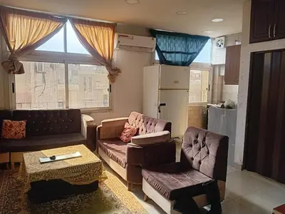 a living room with a couch and chairs and a refrigerator at Hana Home in Amman