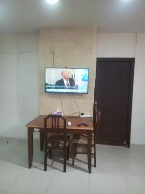 a table with a chair and a tv on a wall at Hana Home in Amman