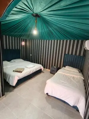 two beds in a room with a green tent at Hillawi Desert Camp Wadi Rum in Disah