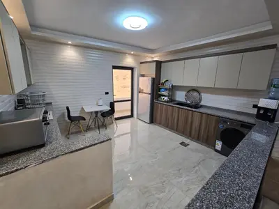 a kitchen with a counter and a table and chairs at الياقوت للشقق الفندقية