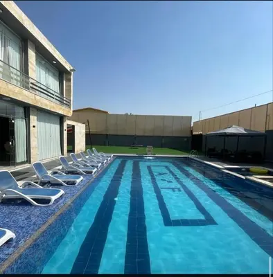 a large swimming pool with lounge chairs next to a building at Qubaisi chalet in Al Rama