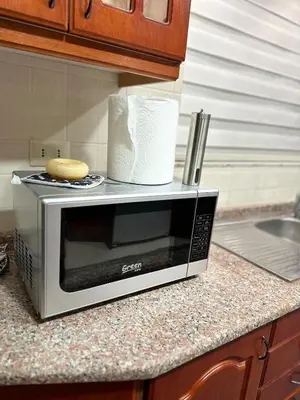 a microwave sitting on a kitchen counter with a cookie at Welcome to our prime location flat in Amman