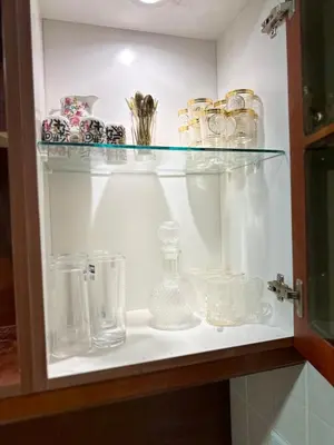a shelf with glass dishes and other items on it at Welcome to our prime location flat in Amman