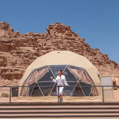 a woman standing in front of a dome tent at A luxurious experience under the stars of Wadi Rum in Wadi Rum