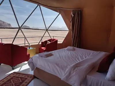 a bed and two chairs in a room with a window at Star Gate Camp in Wadi Rum