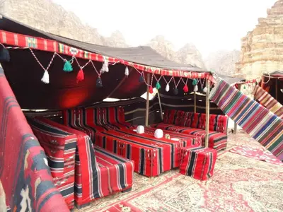 a group of red chairs under a tent at Hillawi Private Bedouin Camp in Wadi Rum