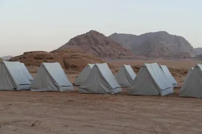 a row of white tents in the desert at Hillawi Private Bedouin Camp in Wadi Rum