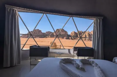 a bedroom with a large window with a view of the desert at Echo of the Sands in Wadi Rum