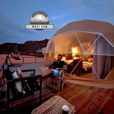 a man sitting in a tent on a deck at WADI RUM RESERVE BUBBlE CAMP in Wadi Rum