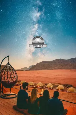 a group of people sitting in front of a view of the desert at WADI RUM RESERVE BUBBlE CAMP in Wadi Rum