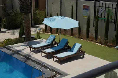 two chairs and an umbrella next to a pool at Atlantis The Palm Villa in Al Rama