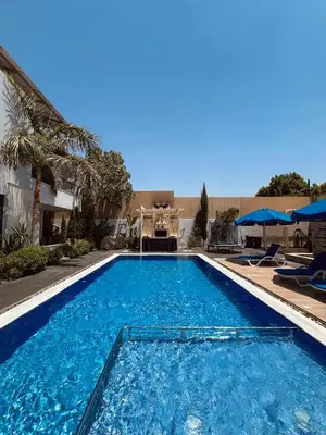 a large blue swimming pool with chairs and umbrellas at Mirabella Villa in Al Rama