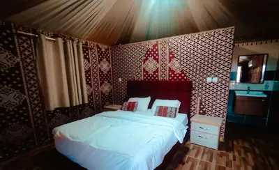 a bedroom with a bed with white sheets and red walls at Solar Soul Camp - Wadi Rum Desert Experience & Stargazing in Wadi Rum