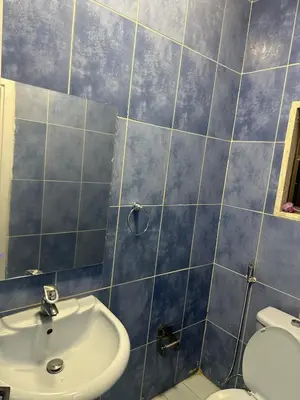 a blue tiled bathroom with a sink and a toilet at Rasheed pearl in Amman