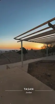 a shelter on the beach with the sunset in the background at البترا Petra in Abū al Lasan