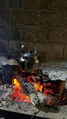 a tea kettle on top of a stove with fire at البترا Petra in Abū al Lasan