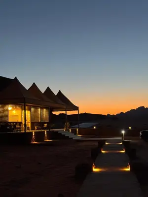 a building with lights in the desert at sunset at Dawn Rum Luxury Camp in Wadi Rum
