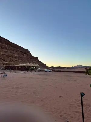 a beach with a building and a car in the sand at Dawn Rum Luxury Camp in Wadi Rum