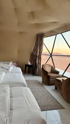 a bedroom with two beds and a chair and a window at Dawn Rum Luxury Camp in Wadi Rum