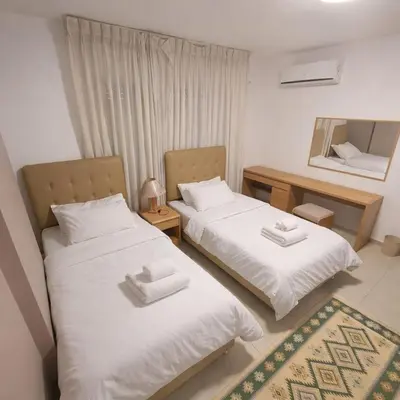 two beds in a room with a mirror at Mecca Street Cozy Apartment in Amman