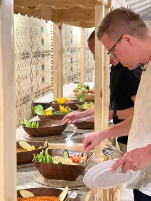 a couple of people preparing food in a buffet at Victoria rum Luxury camp in Disah