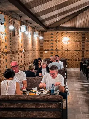 a group of people sitting at a table in a restaurant at Victoria rum Luxury camp in Disah