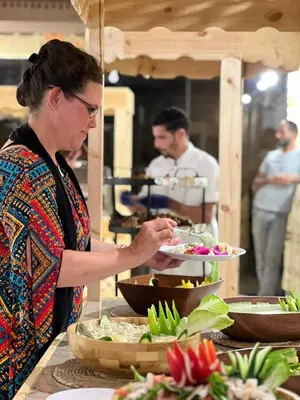 a woman holding a plate of food on a buffet at Victoria rum Luxury camp in Disah