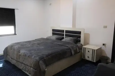 a bedroom with a large bed and a night stand at شقق الاستقلال in Amman