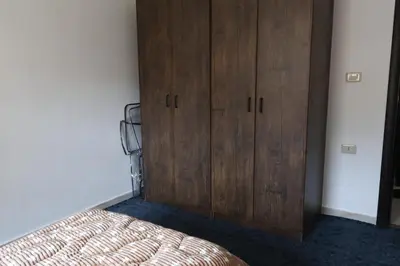 a bedroom with a wooden cabinet next to a bed at شقق الاستقلال in Amman