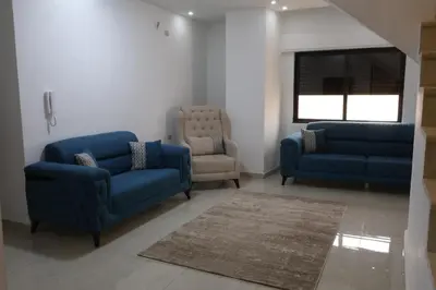 a living room with two blue couches and a chair at شقق الاستقلال in Amman